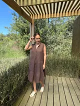 Vestido celeste de lino, sin mangas, con cuello mao y botones de nácar. Presenta varios cortes en su largo, aportando movimiento y un toque moderno a este diseño fresco y elegante.