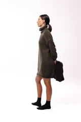 Vestido de punto color beige, de corte holgado y diseño oversized, con cuello alto tipo polera y mangas largas.