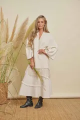 Saco color arena con cuello en V, mangas anchas y diseño holgado. Presenta detalles de flecos en la parte inferior.