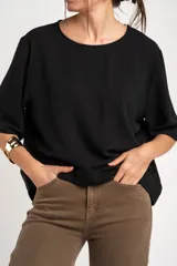 Blusa negra de manga corta y cuello redondo, confeccionada en tejido ligero y fluido.