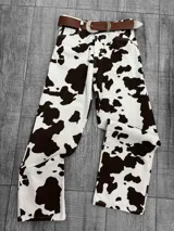 Pantalón de jean blanco con estampado de manchas de vaca en color marrón. Corte recto, tiro alto y cinturón de cuero marrón con hebilla plateada.