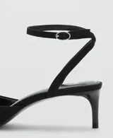 Zapato tipo kitten heel color negro, con punta fina y detalle de pompones en el empeine. Cuenta con una tira ajustable con hebilla en el tobillo.