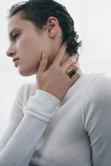 Anillo de diseño geométrico en tono dorado con una pieza rectangular de piedra ojo de tigre incrustada en el centro.