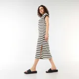 Vestido largo de punto a rayas horizontales blancas y negras, con mangas cortas, cuello tipo polo negro y escote en V.