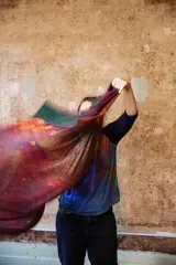 Chal de tul con estampado abstracto en tonos verde, naranja y fucsia. Diseño asimétrico de un solo hombro.