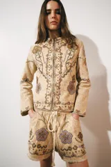Chaqueta de hilatura de algodón en color beige, de cuello redondo y manga larga, con aplicaciones de bordados a contraste.