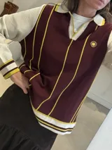 Remera de punto estilo polo con cuello y mangas largas en color crema, cuerpo en color bordó con rayas verticales amarillas y bordado circular en el pecho.