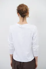 Remera de manga larga color blanco, con cuello redondo y diseño de bordado lineal en el centro del pecho que representa elementos de desayuno.