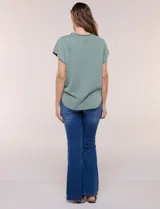 Remera de silueta amplia y relajada confeccionada en algodón y poliéster, de color verde, con escote a la base y mangas cortas de hombro caído. Presenta dobladillo enrollado y ruedo curvo.