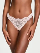 Tanga de encaje color rosado claro, de tiro bajo, con detalle de roseta en el centro.