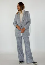 Blazer de lino y algodón, color gris jaspeado, de corte recto y holgado, con solapas de muesca y un solo botón frontal. Se combina con pantalón a juego y un suéter de cuello alto color crema.