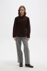 Camisa de pana color marrón, con cuello camisero, cierre frontal de botones y bolsillos en el pecho. Presenta un corte entallado y mangas largas.