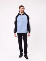 Canguro con capucha de estilo deportivo, con cuerpo en color celeste y mangas raglán en color negro. Presenta el logo de la marca estampado en el pecho, bolsillo tipo canguro frontal y franjas blancas laterales en las mangas.