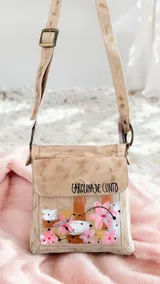 Bandolera de cuero color beige con diseño pintado a mano de flores y arte abstracto, de la marca Carolina De Cunto. Cuenta con correa ajustable y herrajes metálicos color oro viejo.