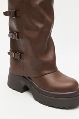 Bota de caña alta estilo biker, color negro, con plataforma robusta y suela dentada. Presenta múltiples tiras laterales con hebillas metálicas ajustables.