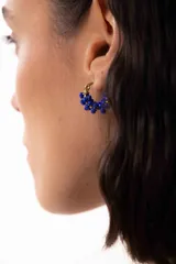 Aro tipo argolla pequeña de acero quirúrgico con mostacillas de color azul enroscadas alrededor de la estructura.