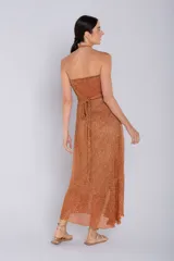 Vestido largo halter color dorado, confeccionado en tejido metalizado con brillo. Presenta escote fruncido al frente y caída fluida.