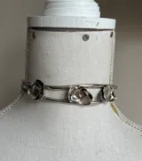 Gargantilla de alpaca plateada con doble aro y tres rosas labradas.