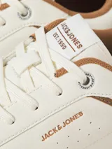 Championes urbanos Jack & Jones modelo Wealing, de diseño clásico con puntera redonda y cordones. Presentan una capellada en color blanco hueso con detalles en tono marrón y beige en el talón y laterales. Cuentan con suela de goma resistente.