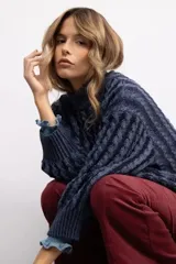 Sweater de punto con diseño de trenzas, cuello alto y silueta relajada. Presenta puños acanalados y un corte oversize.