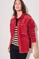 Sobrecamisa de pana color rojo, con cierre frontal de botones, bolsillos delanteros con solapa y ruedo desflecado.