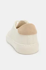 Zapatilla urbana color off-white con detalle trasero en contraste de tono tostado y suela engomada. Presenta pespuntes decorativos en el cuerpo y cierre de cordones.