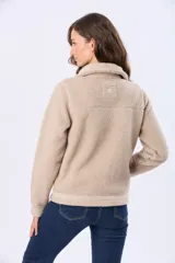 Campera de sherpa color beige, con cuello camisero, cierre frontal con botones a presión y detalles de ribete en la solapa y puños.