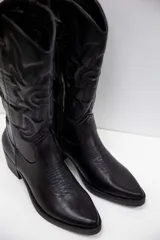 Bota texana de caña media en color negro, con diseño bordado y terminación lisa. Presenta punta fina, taco medio ancho y cierre lateral interno.