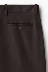 Pantalón de corte relajado confeccionado en una mezcla de algodón y lino. Presenta pinzas frontales, cierre con botón y corchete oculto, bolsillos laterales ribeteados y bolsillos traseros con botón.
