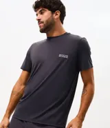 Remera deportiva de hombre color gris oscuro, confeccionada en poliamida con tecnología dry de secado rápido, cuello redondo y manga corta. Presenta una pequeña estampa con texto en el pecho.