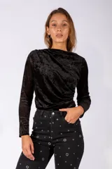 Body de manga larga confeccionado en terciopelo negro, con diseño drapeado en el frente y escote asimétrico.