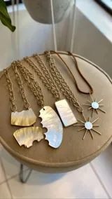 Collar con dije de nácar de forma irregular y orgánica, suspendido de un cordón fino en tono neutro.