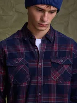 Camisa de pana color azul marino, con mangas largas, cuello clásico y dos bolsillos frontales con solapa y botón.