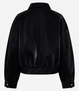 Campera bomber de poliuretano texturizado en color negro, con cuello camisero, cierre frontal, bolsillos aplicados en el pecho y ruedo elástico.