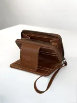 Mini billetera de cuero color marrón con textura combinada, lisa y efecto croco en la solapa. Cuenta con cierre perimetral, múltiples ranuras para tarjetas y una correa de muñeca extraíble.