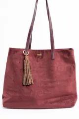 Bolso tipo tote de gran tamaño confeccionado en material sintético con acabado efecto gamuza en color tostado. Presenta doble asa larga en tono contrastante y placa metálica pequeña con logo de la marca en la parte frontal.