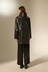 Pilot de efecto cuero negro con acabado brillante, diseño de manga larga, capucha con cordones ajustables y cierre frontal con botones a presión. Cuenta con bolsillos laterales con solapa.