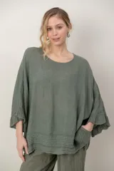 Blusa de lino color verde militar, holgada, de manga 3/4 con volados en los puños, cuello redondo y detalle de alforzas horizontales en el dobladillo.