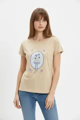Remera de algodón color beige, de manga corta con vuelta, cuello redondo y estampa frontal de flores con lazo en tonos azules y celestes.