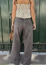 Pantalón jean azul oscuro, de corte wide leg y tiro medio. Presenta detalles de costuras diagonales en la parte superior.