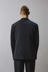 Blazer de corte regular fit confeccionado en tejido técnico y transpirable de color negro, con cuello de solapas de muesca, cierre frontal de un botón y bolsillos con solapa en la cadera.