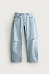 Jeans de corte barrel fit confeccionados en denim de algodón rígido, con diseño de cinco bolsillos y cierre frontal con botones. Presentan un lavado claro con efecto de roturas en las perneras.