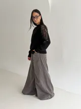 Sweater negro de tejido de punto con cuello redondo y mangas largas. Presenta detalles de transparencias y apliques bordados con pedrería en la parte superior de las mangas.