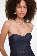 Top strapless de denim azul oscuro con escote corazón, costuras pespunteadas en color contrastante y corte peplum.