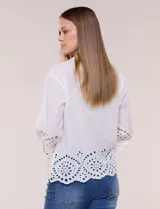 Camisa de calce holgado color blanco, confeccionada en tejido liviano de algodón, con cuello camisero clásico, mangas tres cuartos y terminación en puños y ruedo con diseño de bordado broderie calado y festoneado.