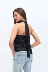 Top de lino color beige, sin mangas, con cuello alto halter y detalles de volados frontales.