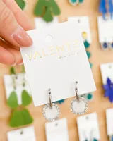 Aros de acero plateado con forma de argolla con dije circular blanco con strass.