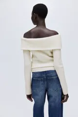 Top de punto acanalado con escote off-the-shoulder y mangas largas. Presenta un diseño ajustado con cuello vuelto y textura acanalada en toda la prenda.