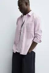 Camisa de corte regular fit confeccionada en tejido de algodón con textura. Presenta cuello solapa, cierre frontal de botones, manga larga con puños abotonados y un bolsillo plastrón en el pecho.