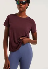 Camiseta deportiva de manga corta en color bordó, confeccionada en tejido técnico transpirable con paneles laterales microperforados para mayor ventilación.